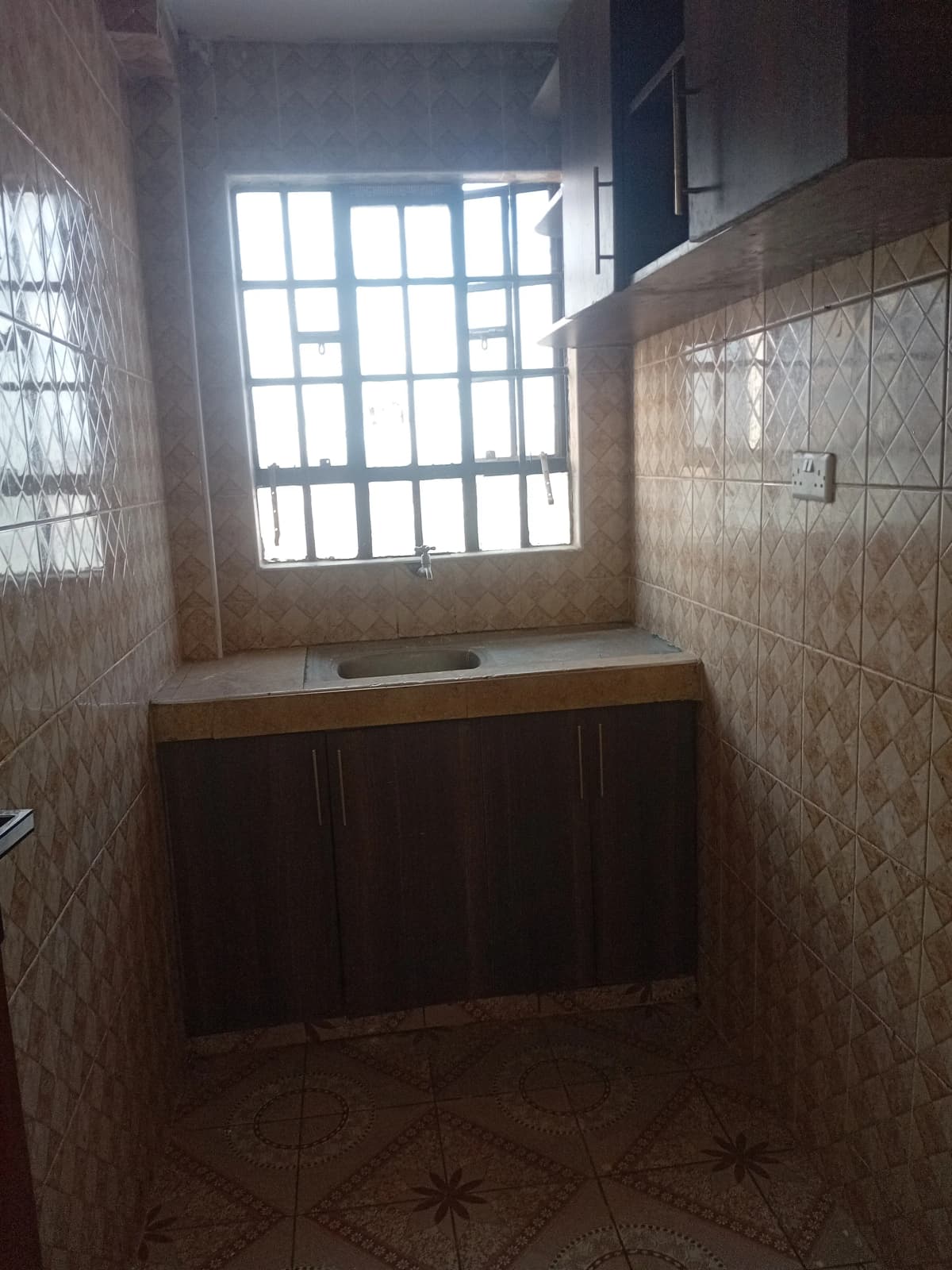 Compact kitchen with dark cabinetry and barred window