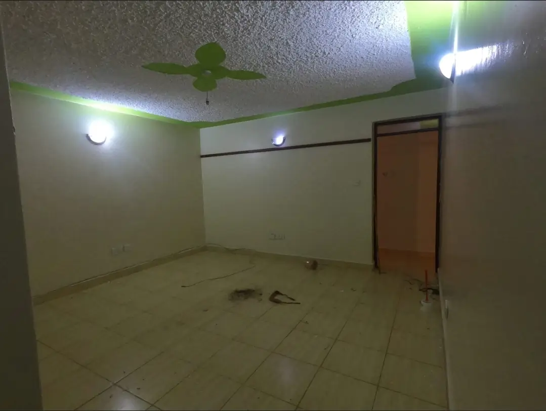 Empty living room with ceiling fan and neutral tiled flooring