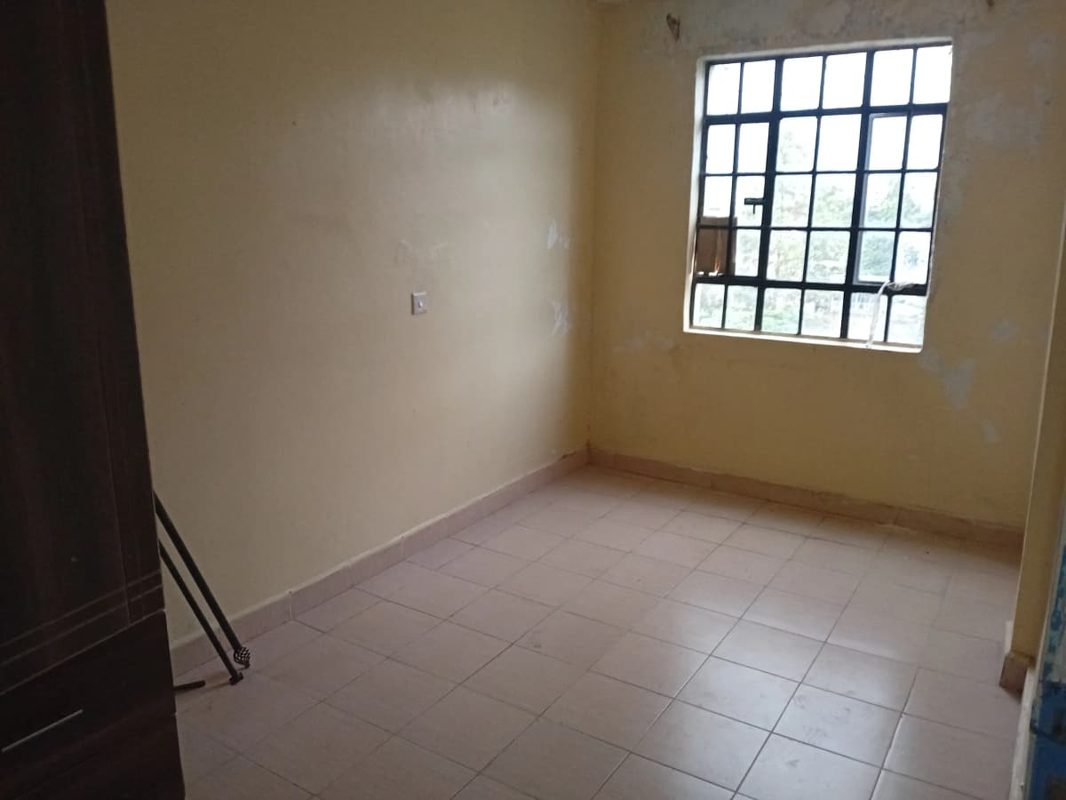 Empty bedroom with tiled floor and barred window