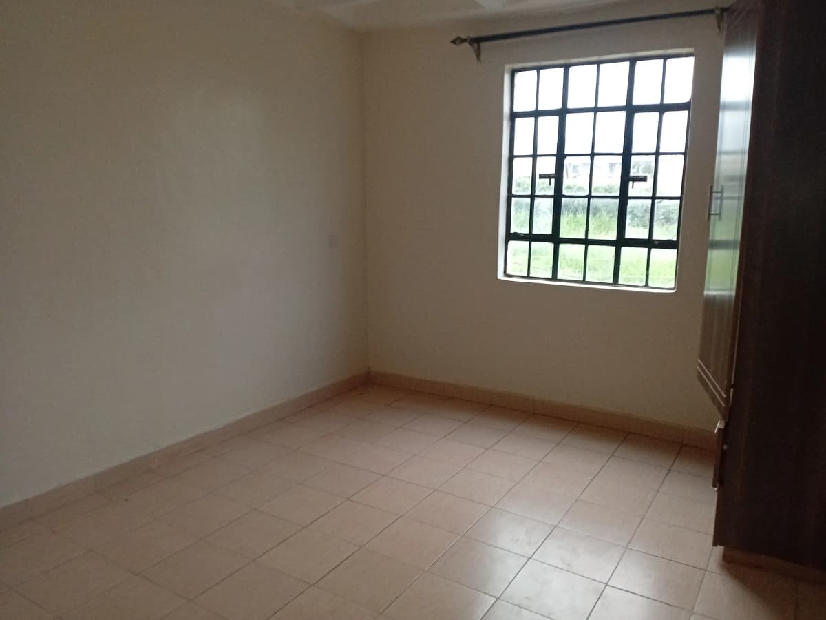 Empty bedroom with tiled floor and barred window