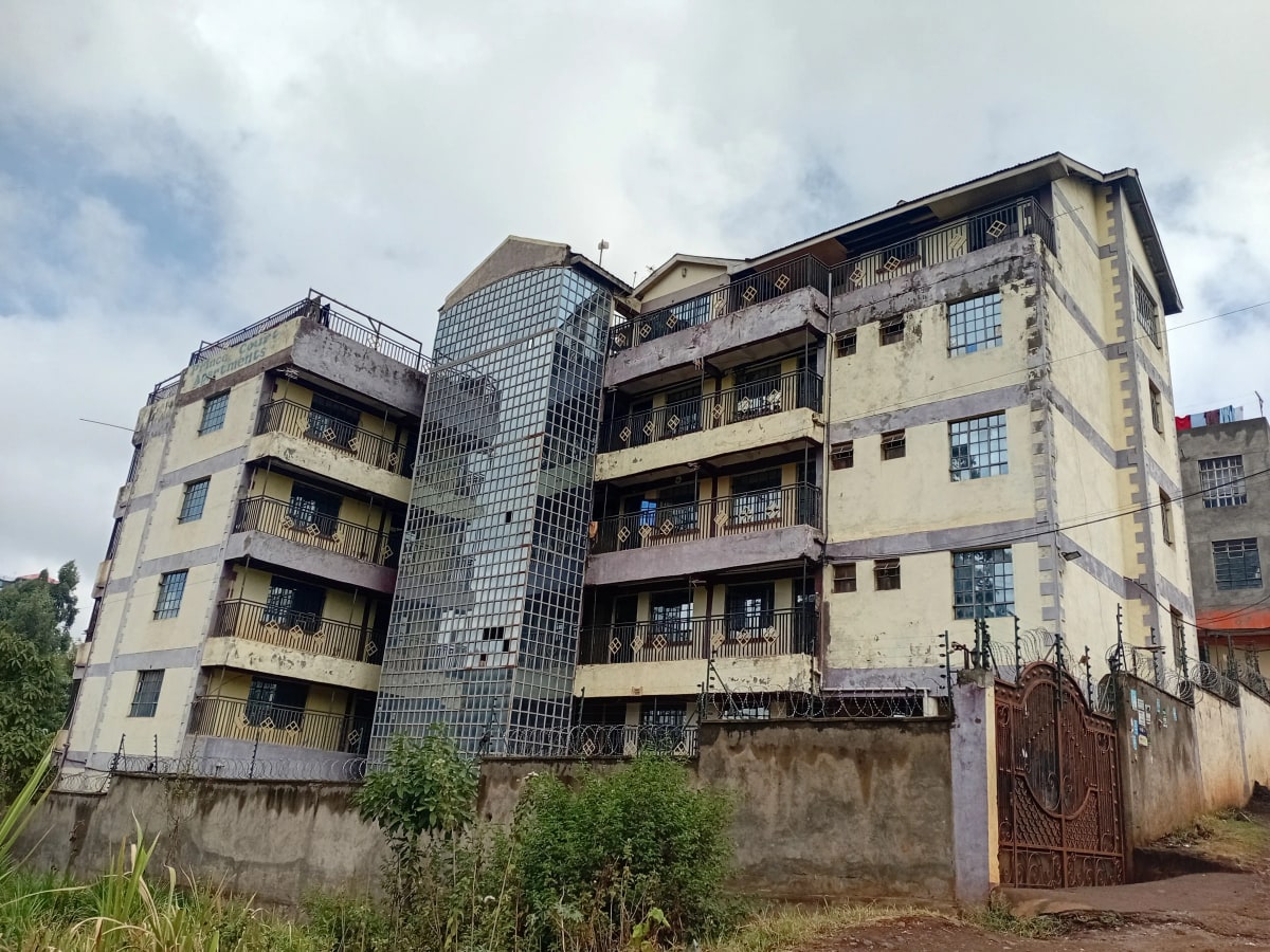 Multi-story residential building facade with balconies and compound wall