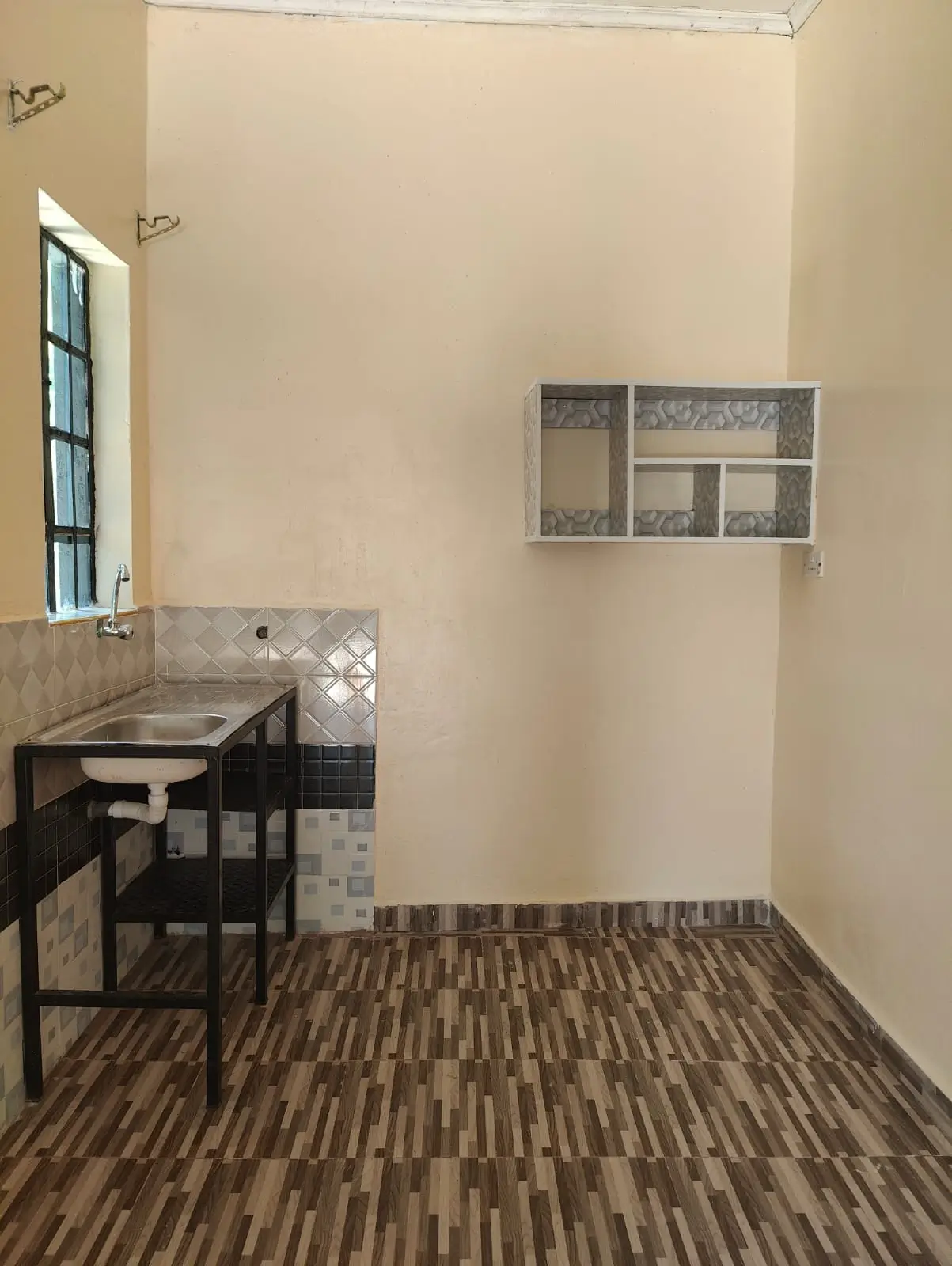 Compact kitchen with sink, black cabinetry, and wall storage
