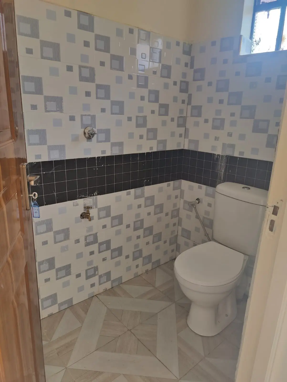 Compact bathroom with patterned tile walls and toilet