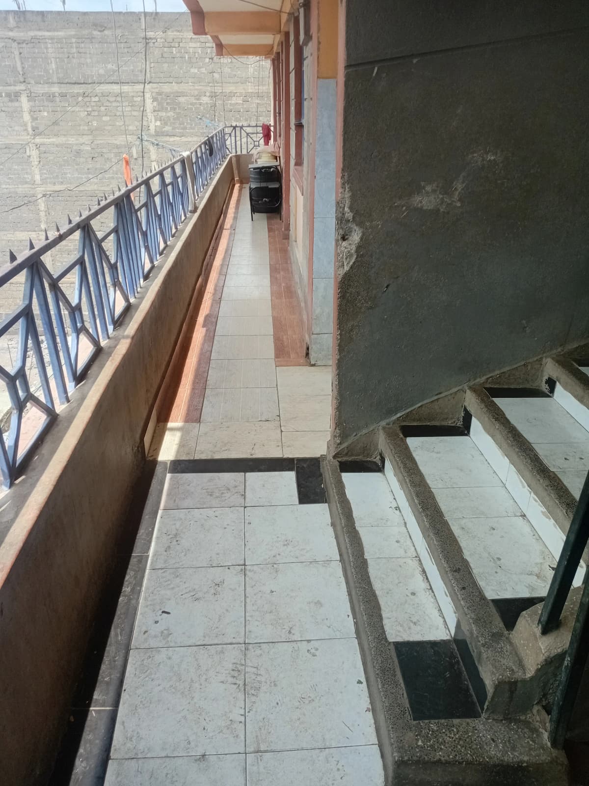 Long narrow balcony with blue railing and tiled flooring