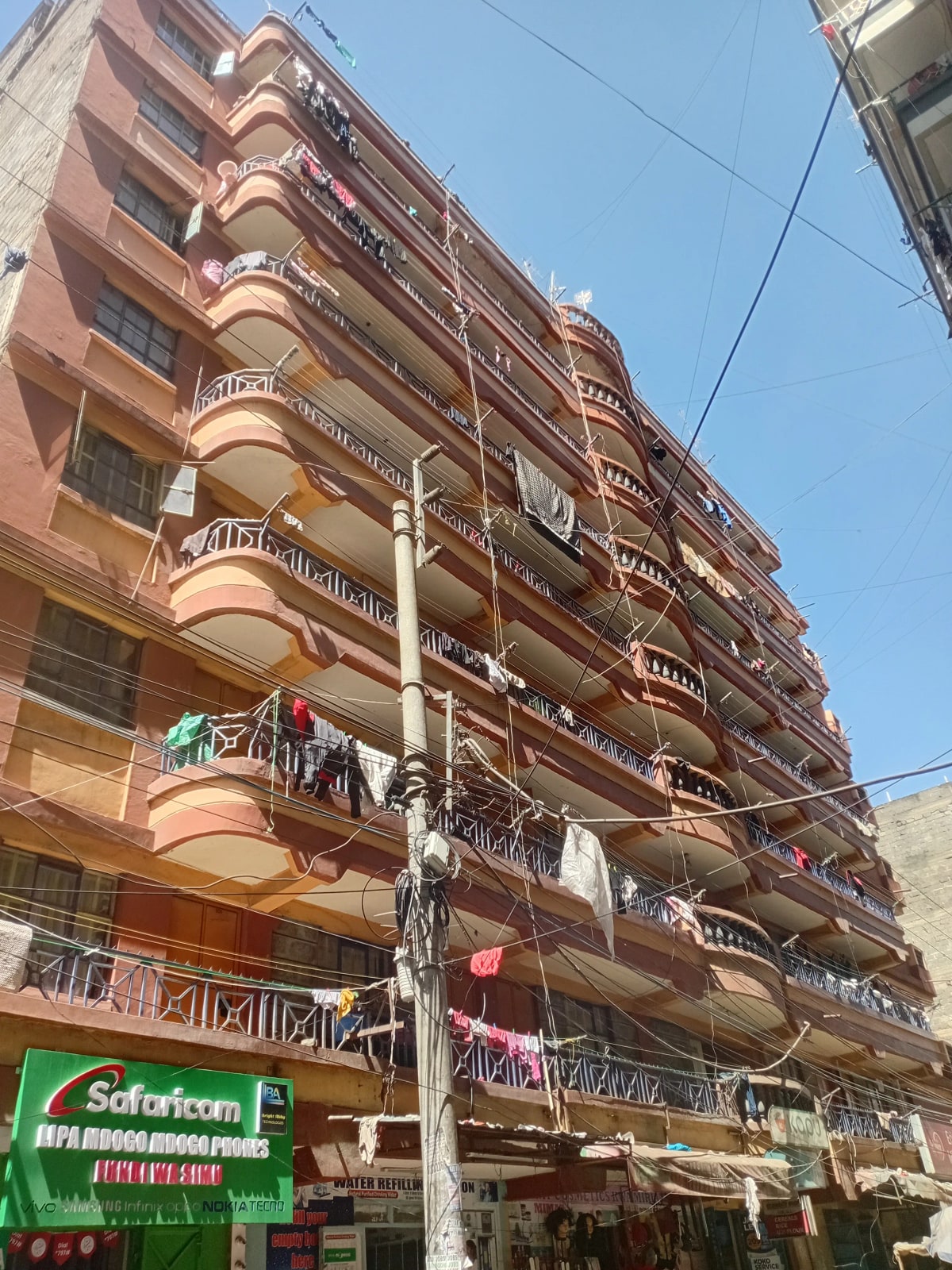 Multi-story residential building facade with balconies and street-level shops