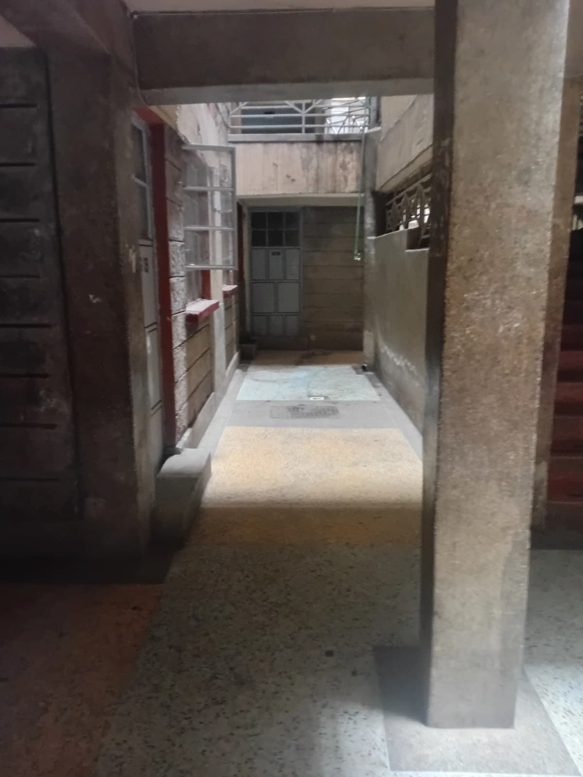 Narrow indoor corridor with concrete walls and skylight