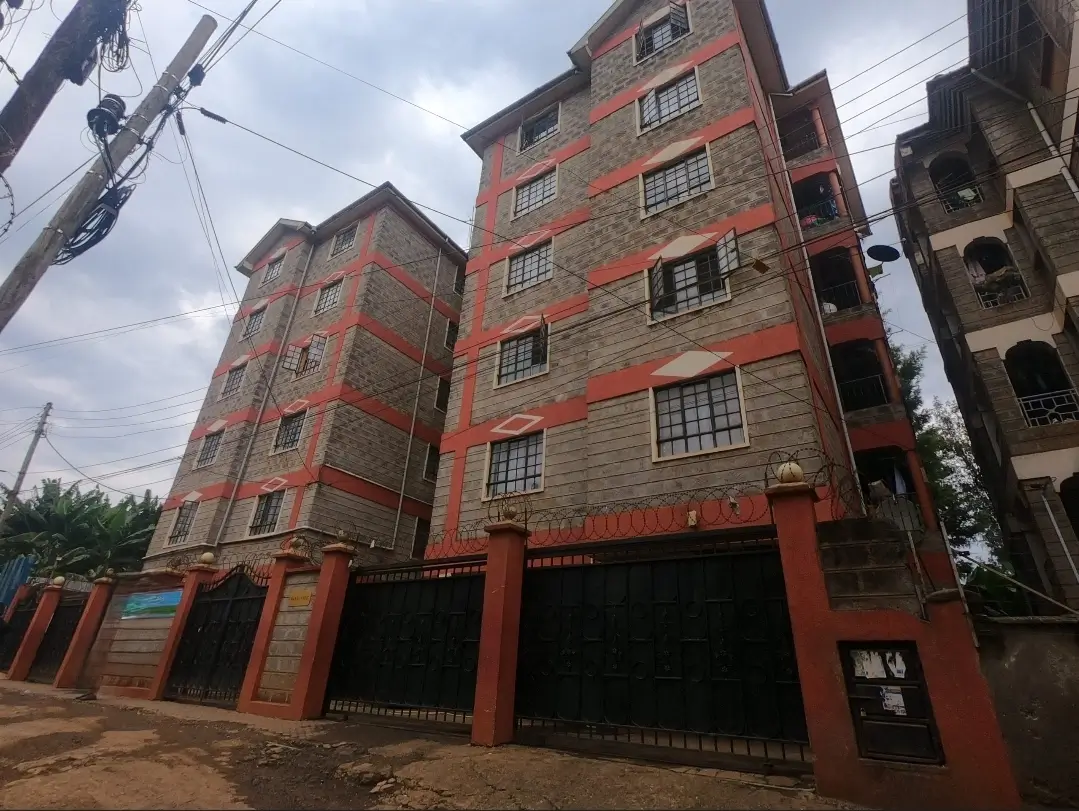 Multi-story residential building with red facade and ground-level parking