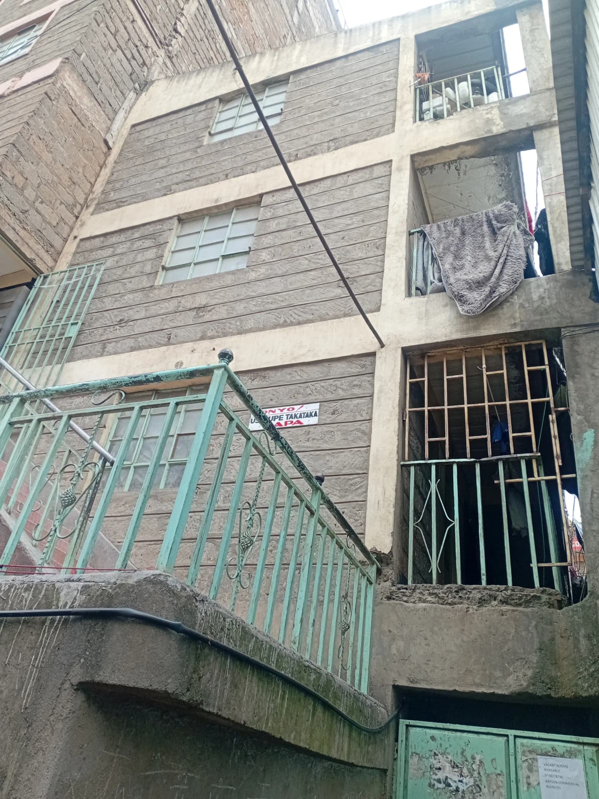 Multi-story residential building facade with metal stairs and gate