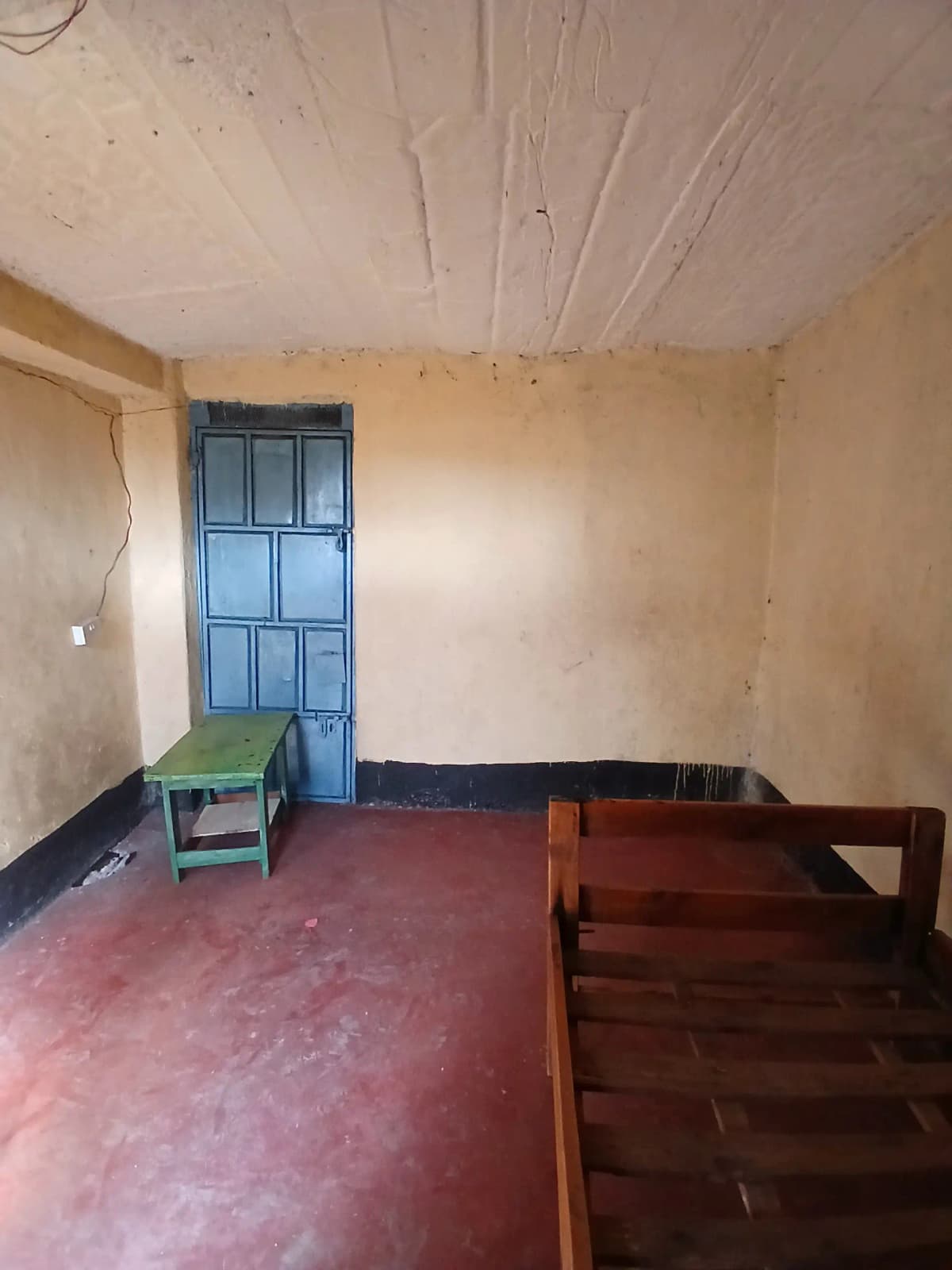Unfurnished living space with red floor and blue door