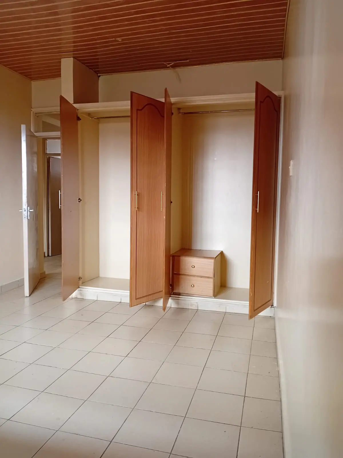 Spacious bedroom with wooden wardrobe and tiled flooring