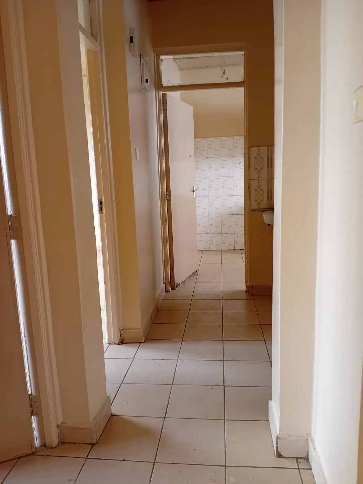 Tiled corridor with neutral walls and open doorways
