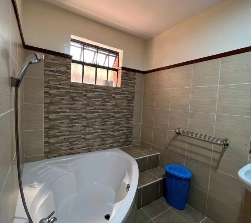Bathroom with soaking tub, tiled shower area, and window