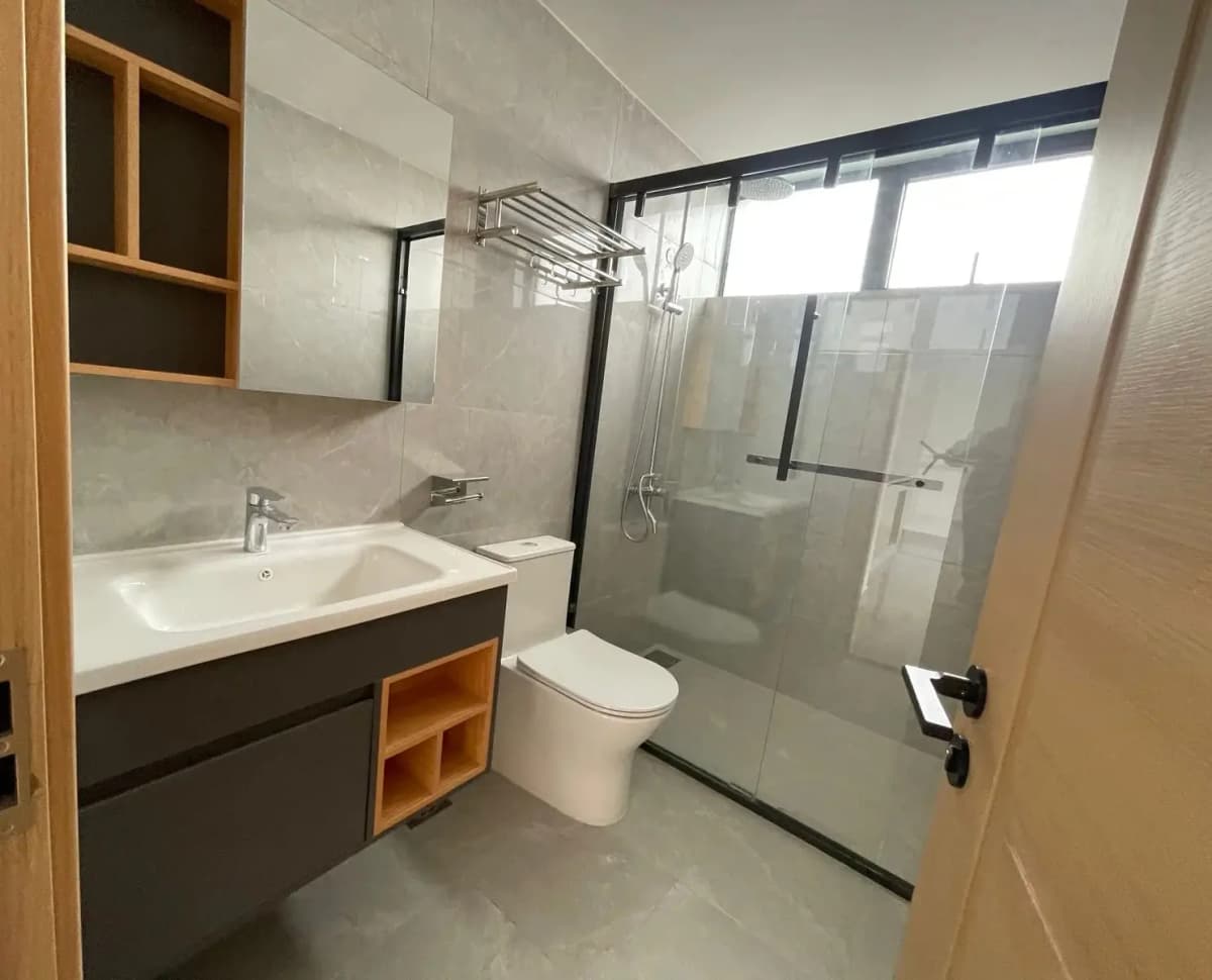 Modern bathroom with dark vanity, glass shower enclosure, toilet