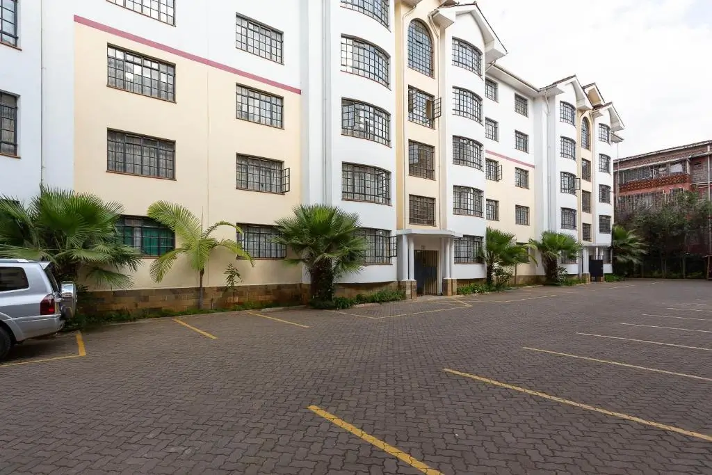 Multi-story residential compound with parking area and landscaping