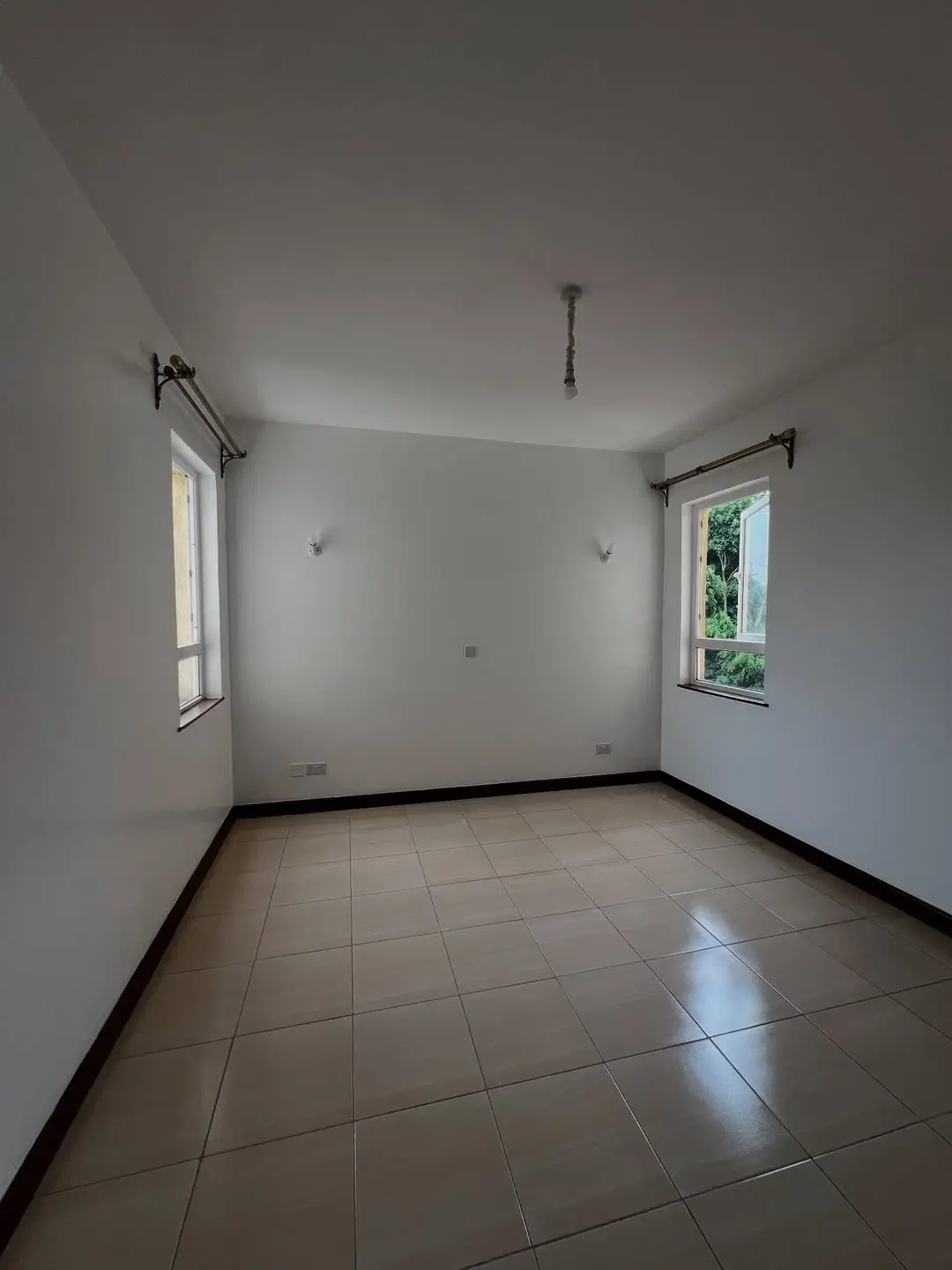 Empty bedroom with tiled floor and two windows