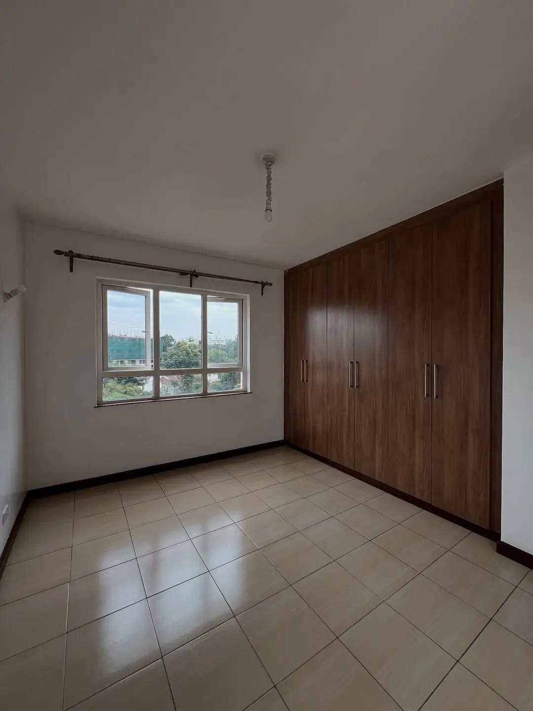 Spacious bedroom with built-in wooden wardrobes and windows