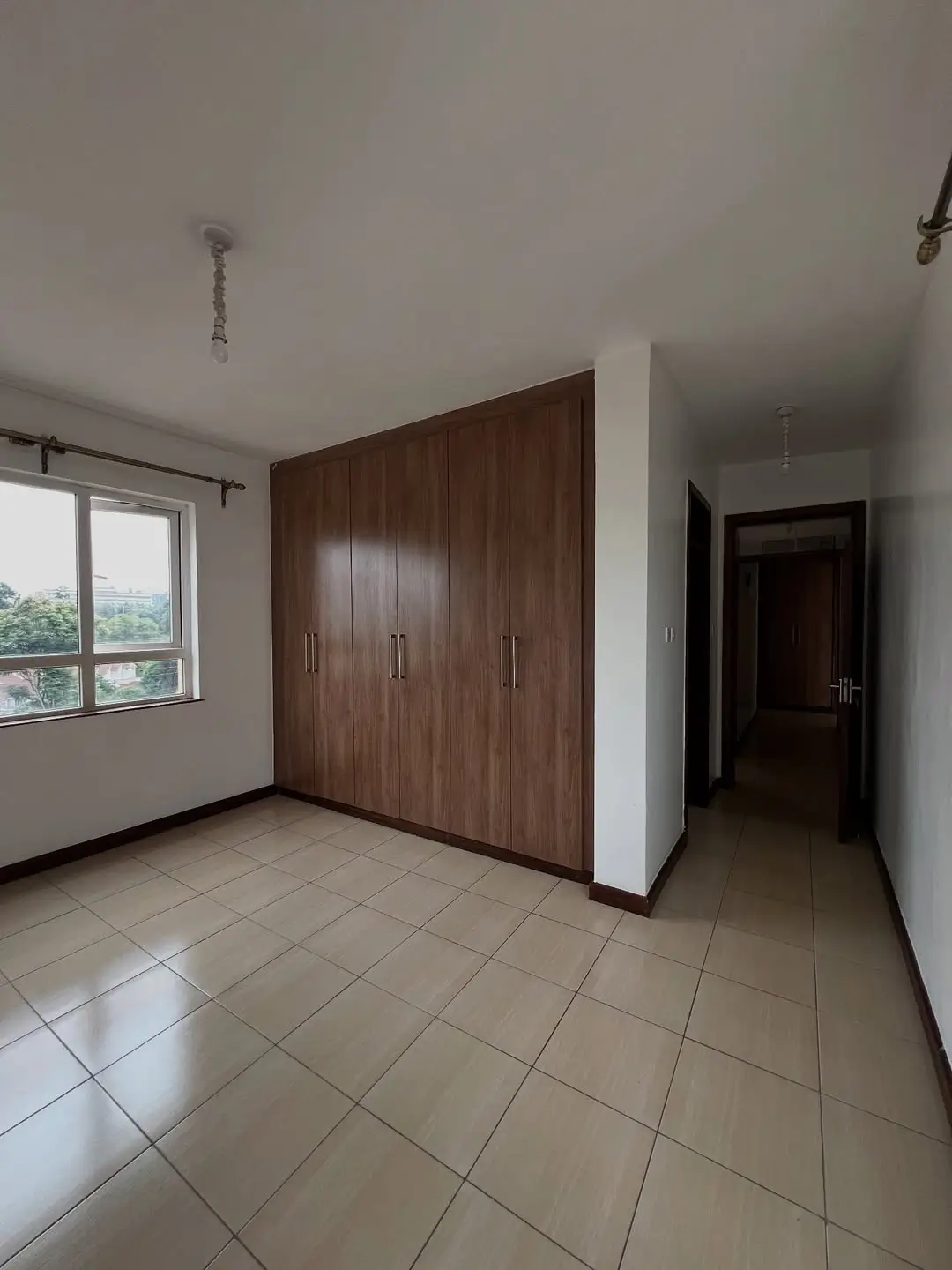 Spacious bedroom with built-in dark wood wardrobe and window