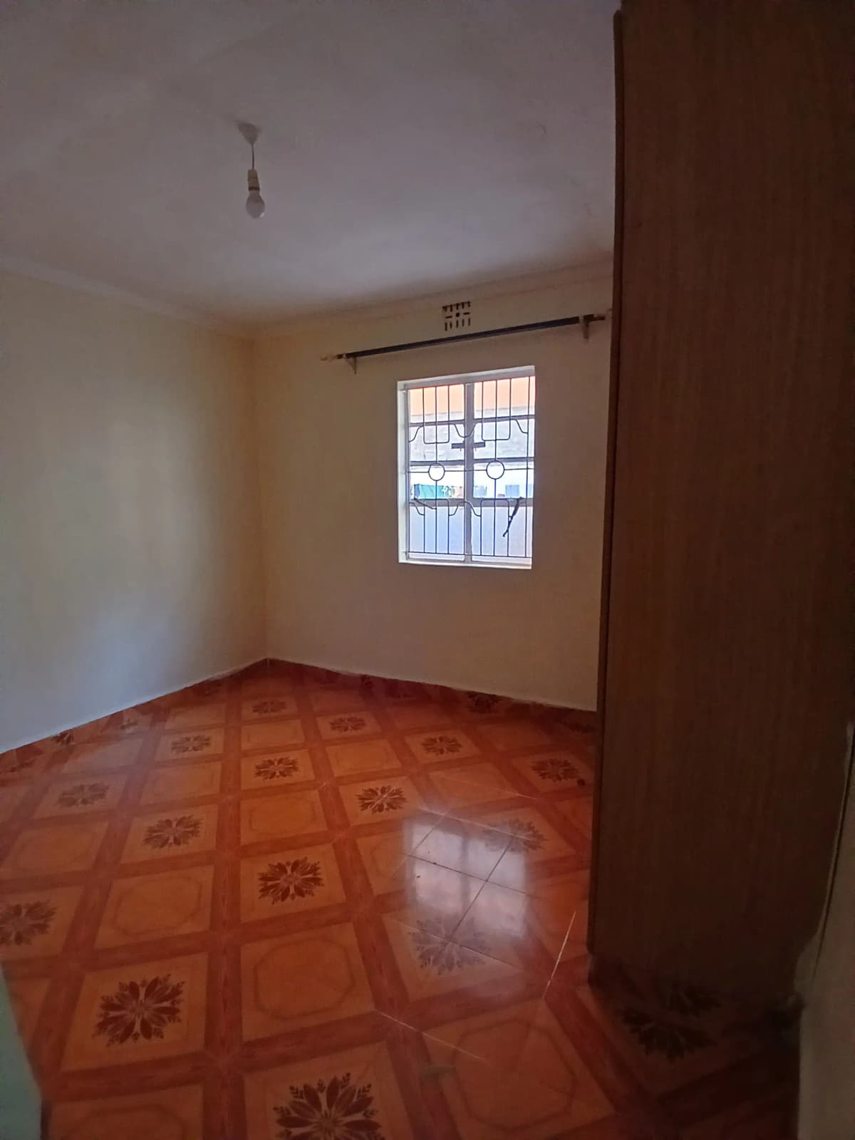 Spacious bedroom with patterned terracotta floor and natural light