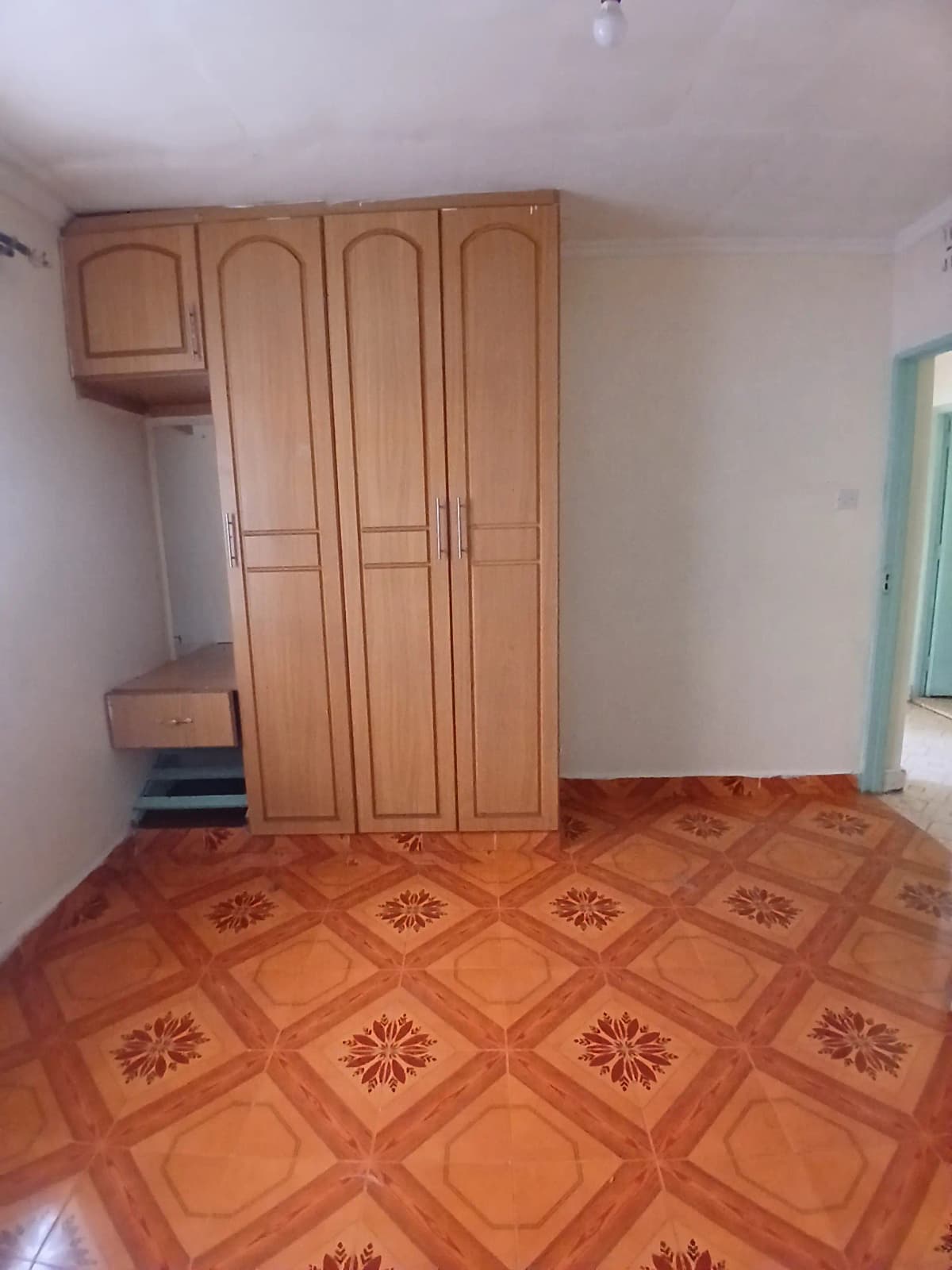 Spacious bedroom with wooden wardrobe and patterned terracotta floor