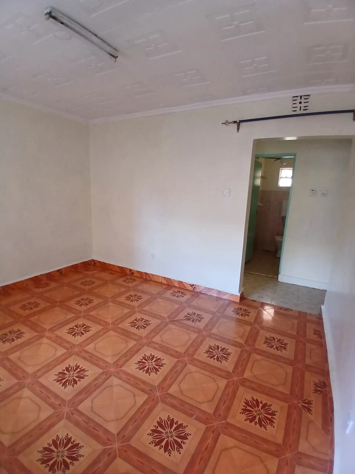 Empty bedroom with patterned terracotta tile flooring
