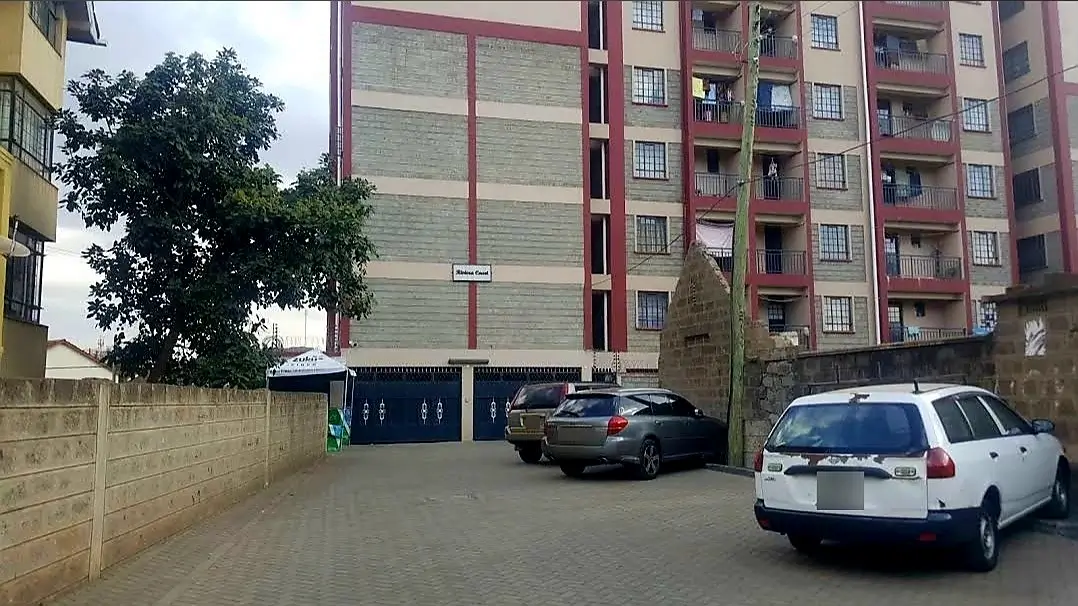 Residential compound parking area with multiple vehicles and buildings