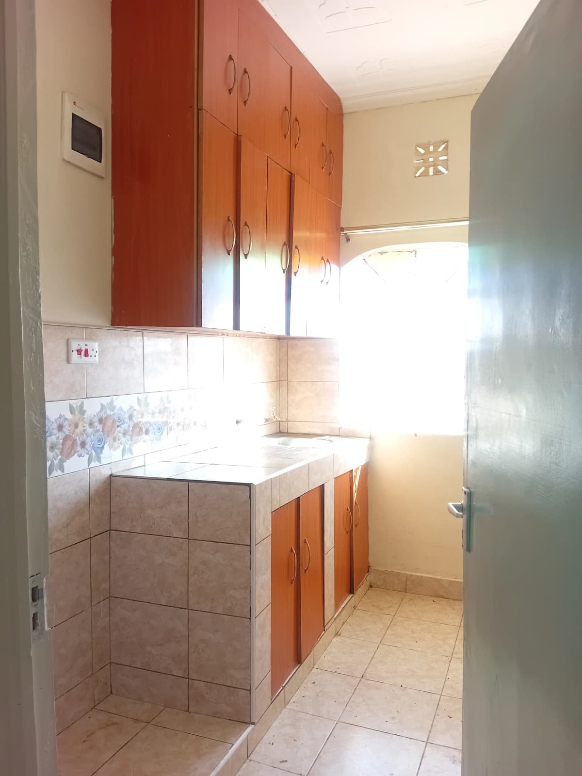 Compact kitchen with red cabinets and white tile countertops