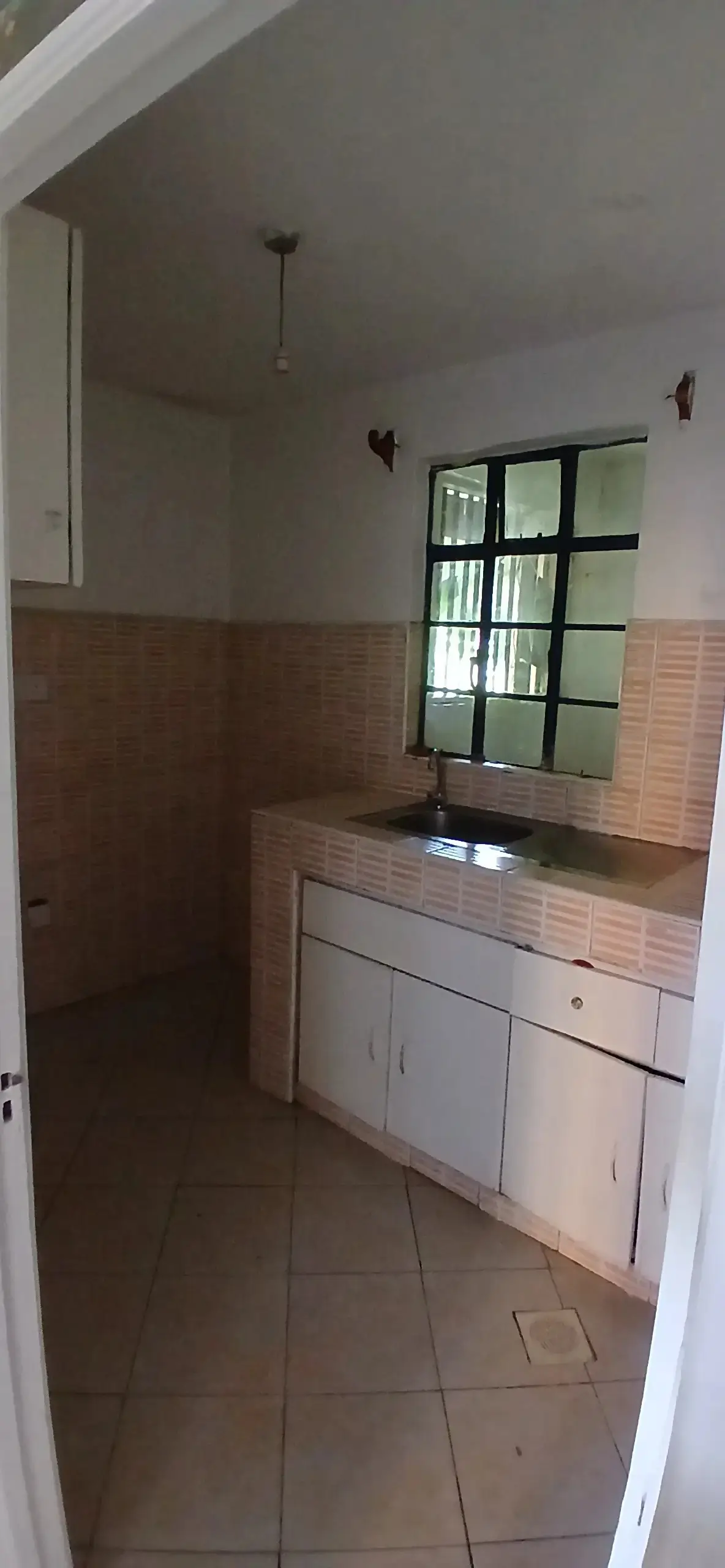 Compact kitchen with white cabinetry and terracotta tile backsplash