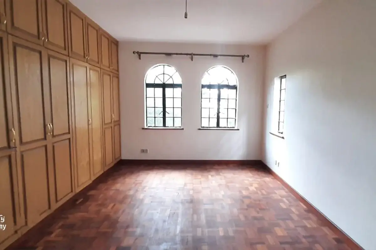 Spacious bedroom with wooden wardrobe and arched windows