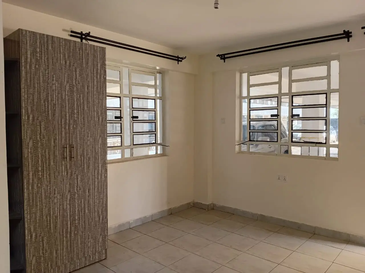 Spacious bedroom with dual windows and built-in wooden wardrobe