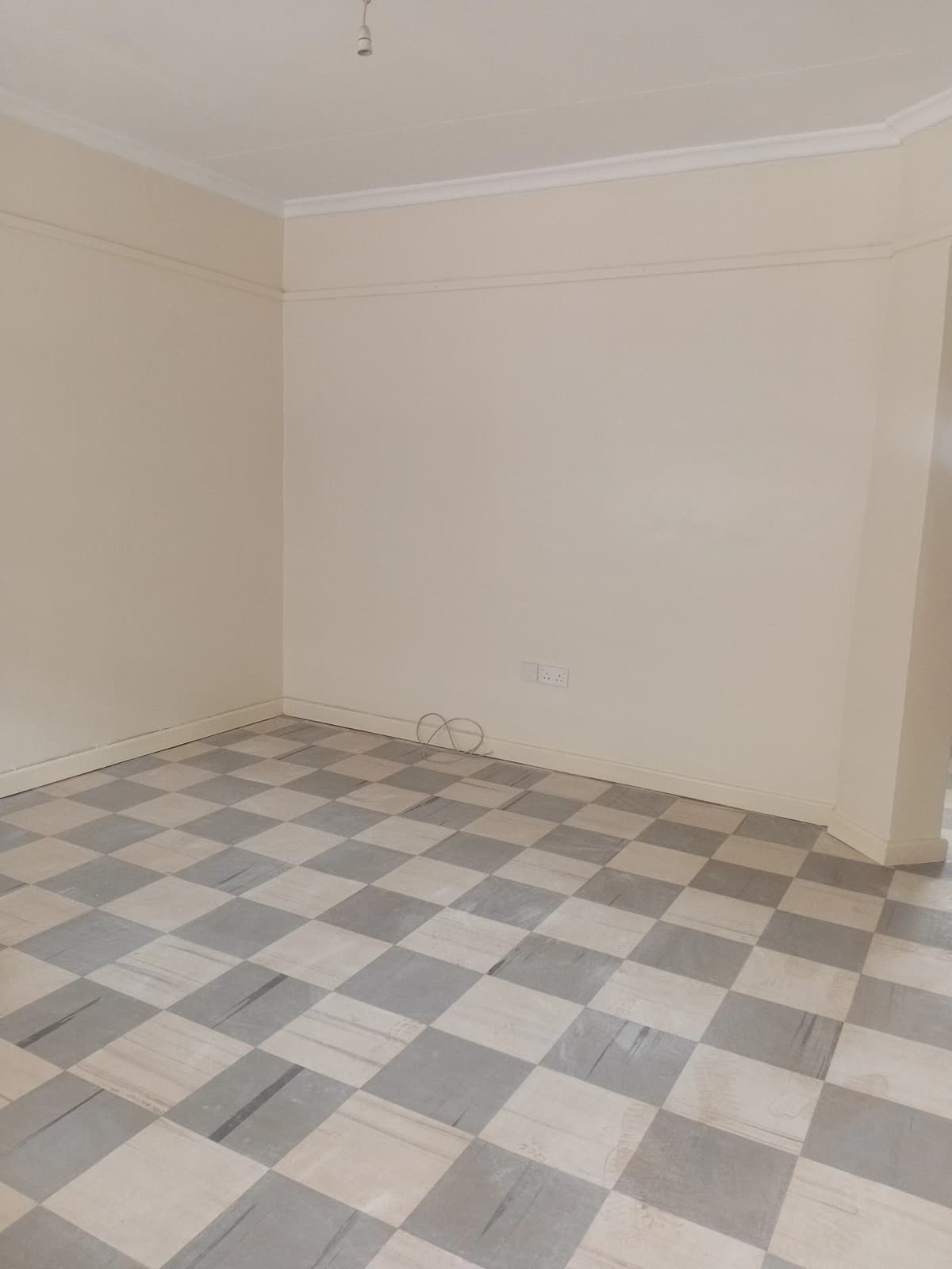 Empty bedroom with checkered tile flooring and bare walls