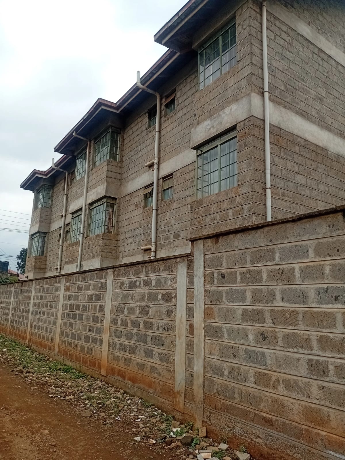 Multi-story brick building with perimeter wall and gate