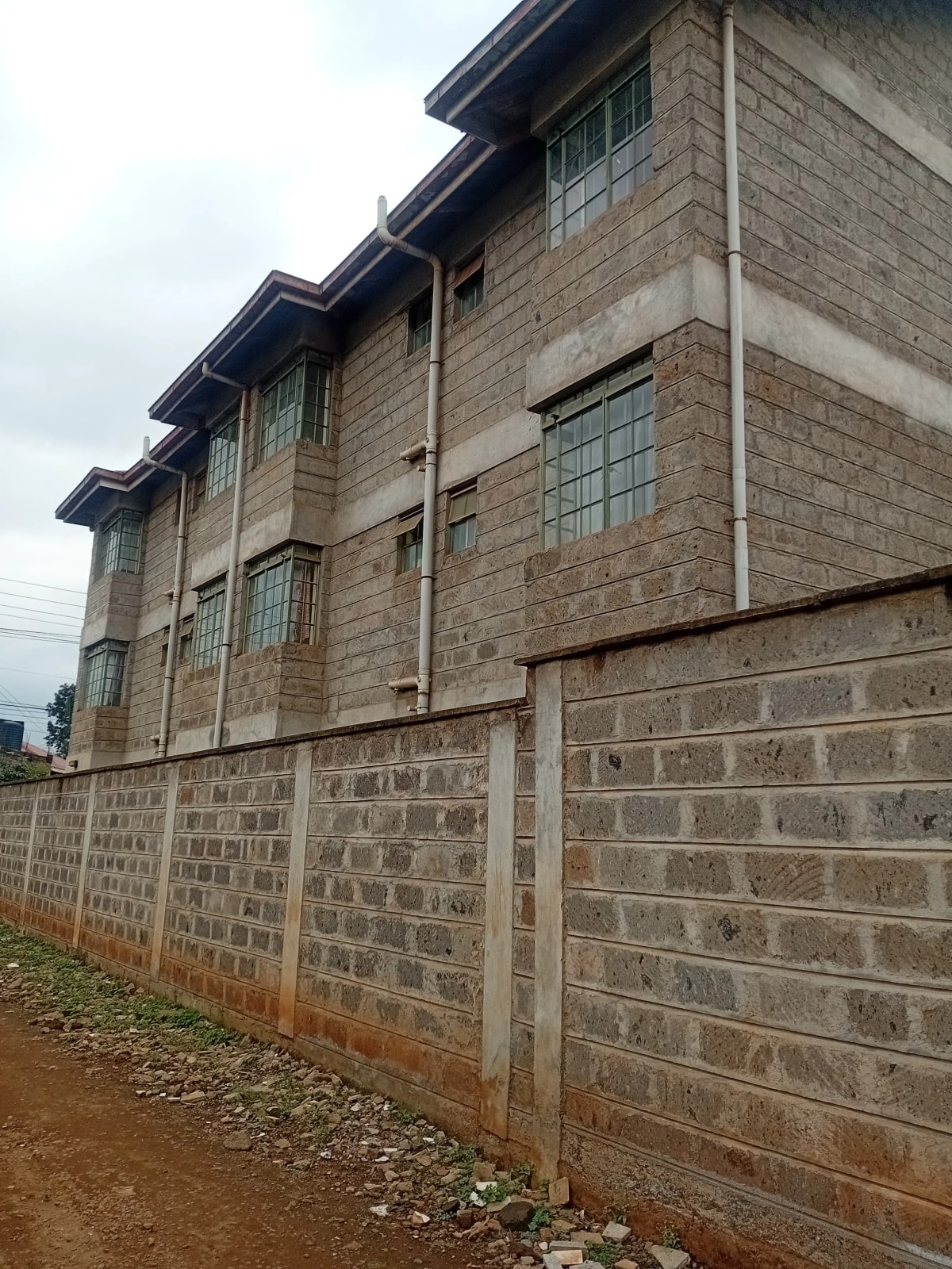 Multi-story brick building with perimeter wall and gate