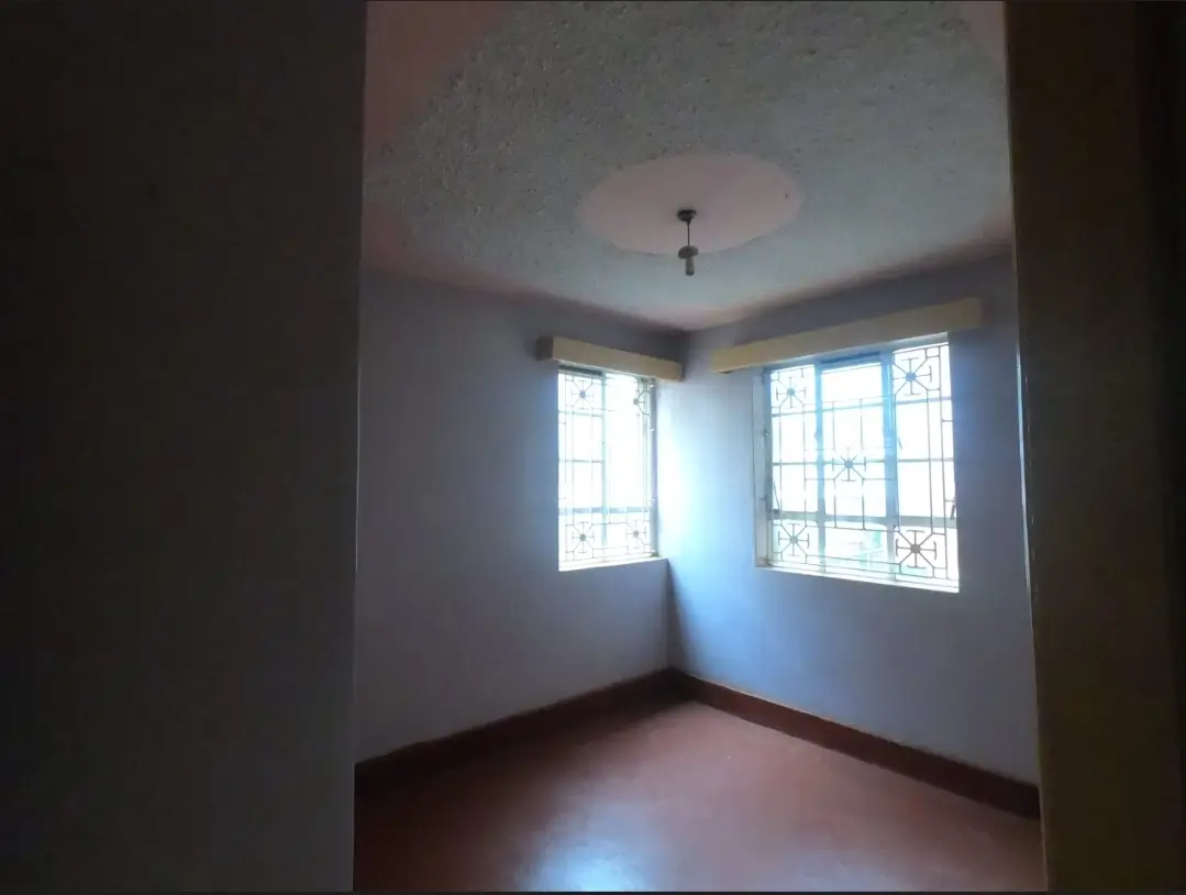 Bright empty bedroom with corner windows and wooden floor