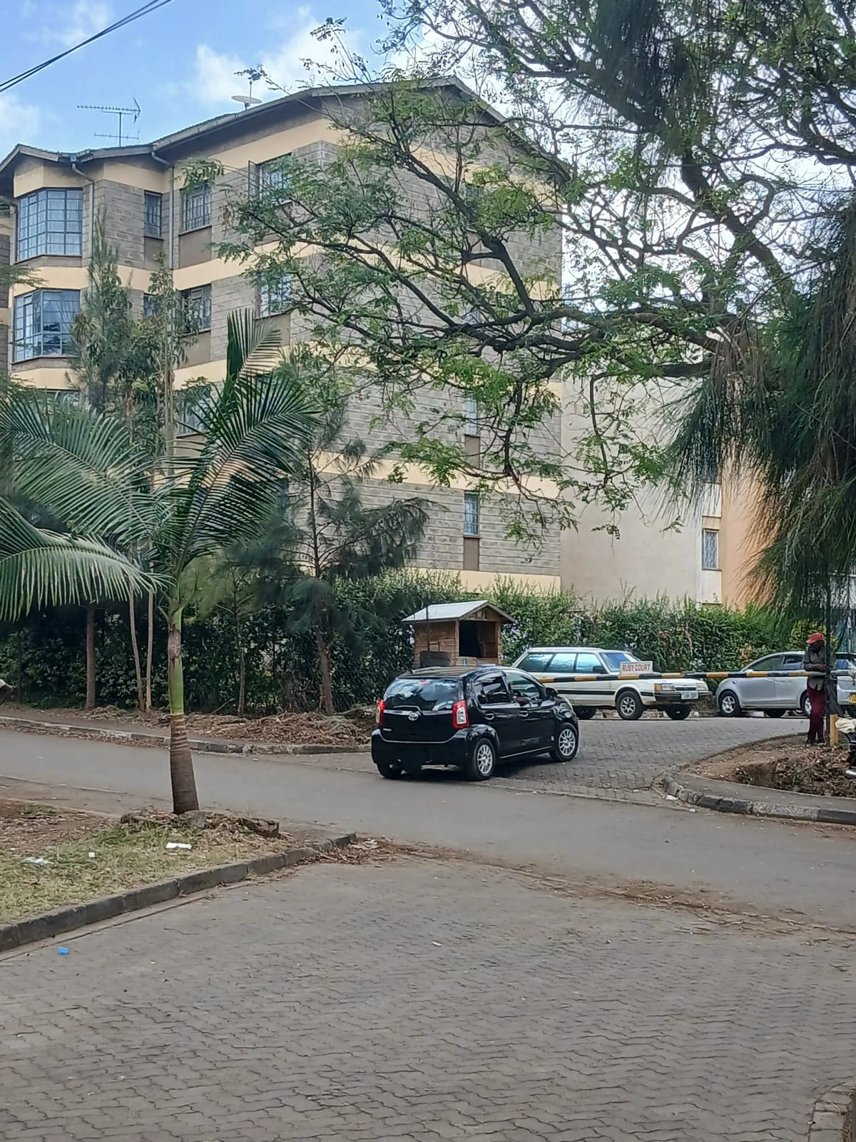 Multi-story residential building with gated driveway and parked vehicles