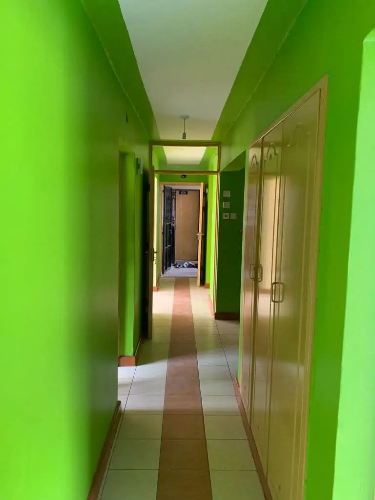 Bright green hallway with multiple doors and tile flooring