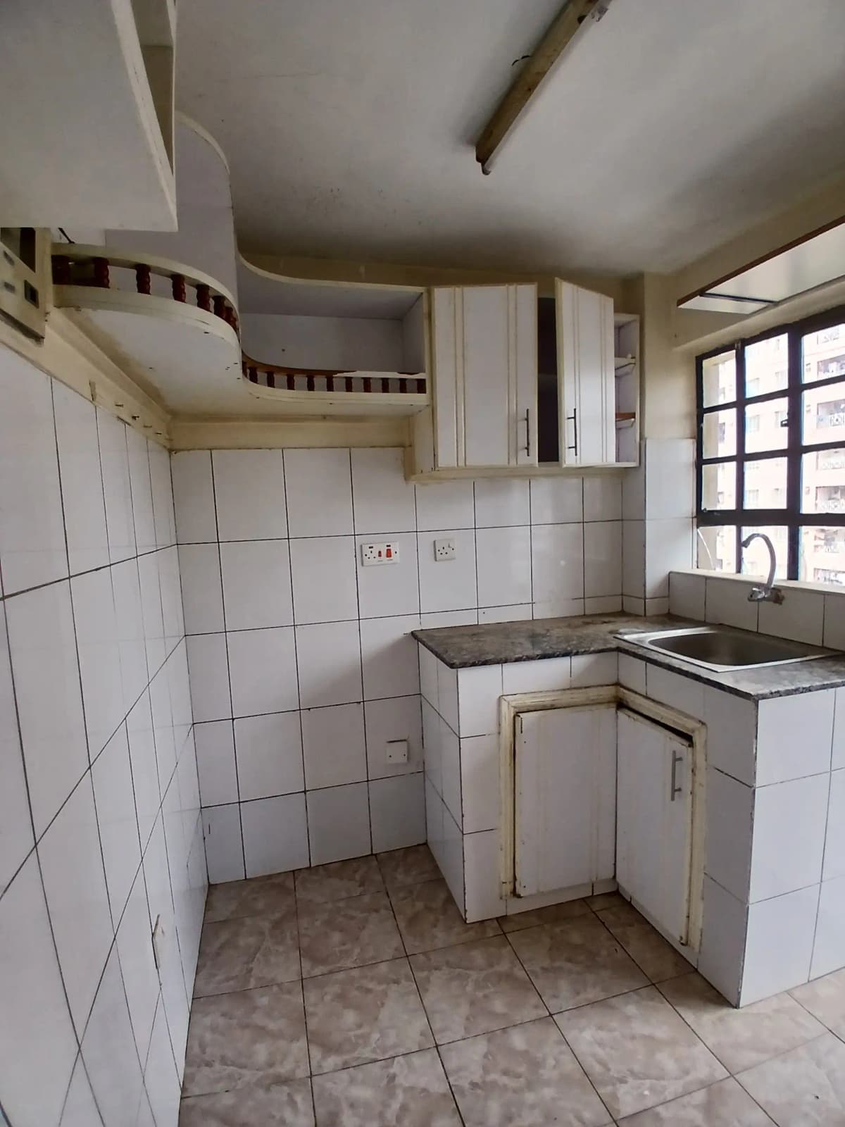 Compact kitchen with white tile walls and basic cabinetry