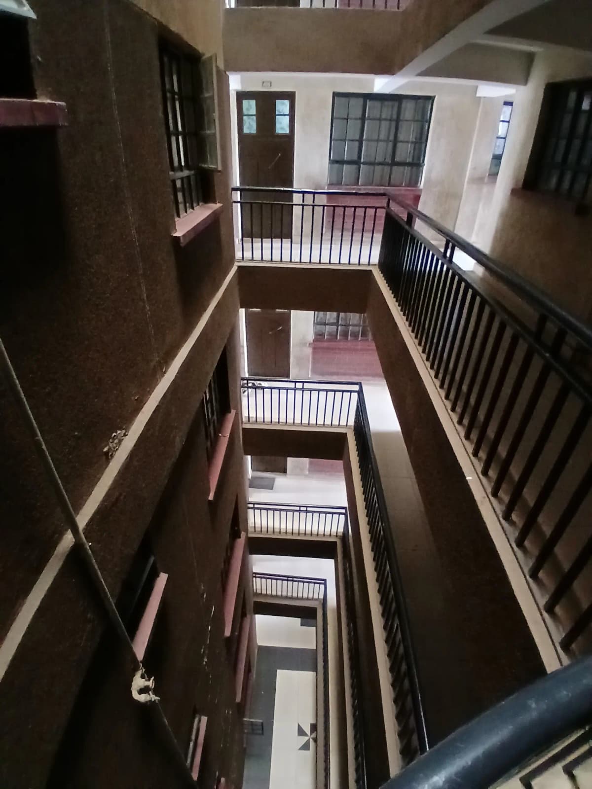 Multi-story internal stairwell with white railings and landings
