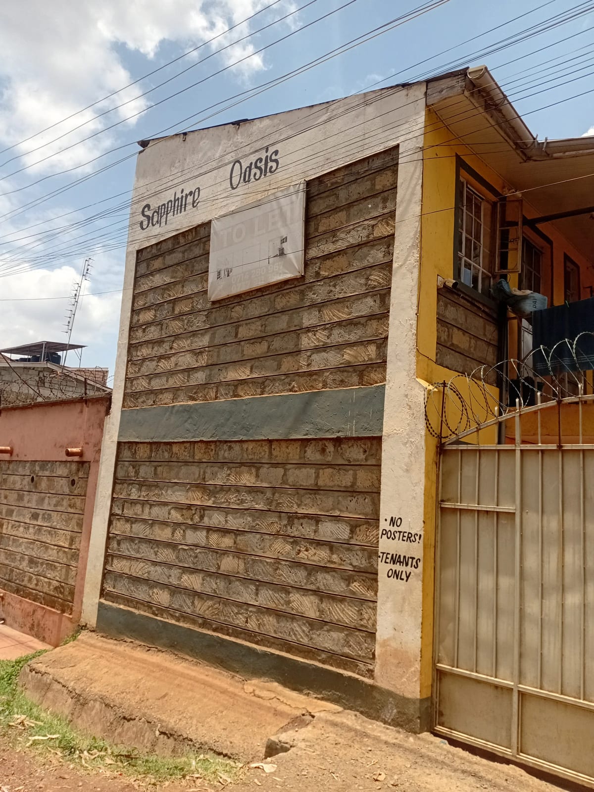 Modest residential building facade with metal shutters and gate