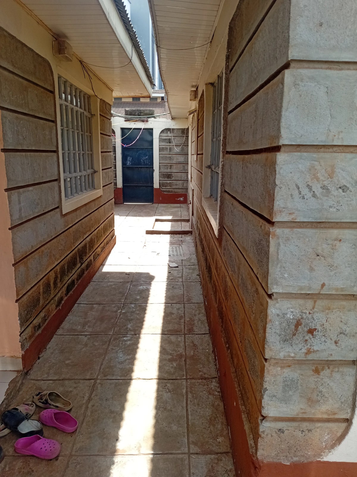 Narrow corridor with tiled floor and wooden door frames