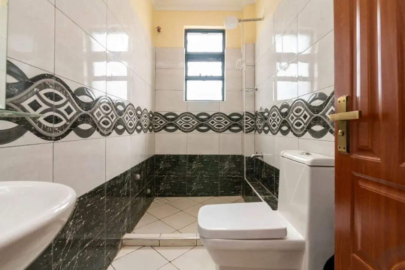 Bathroom with decorative tile border, dual sinks, toilet