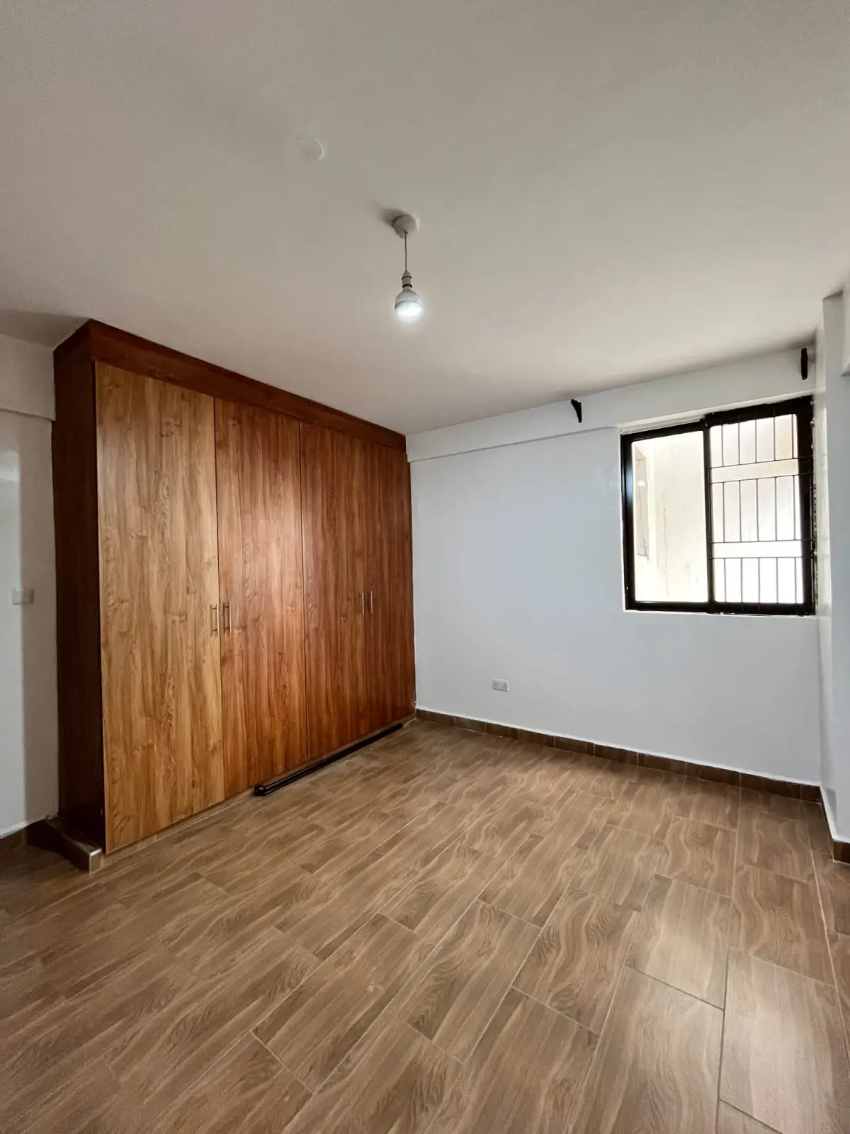 Spacious bedroom with wooden wardrobe and timber flooring