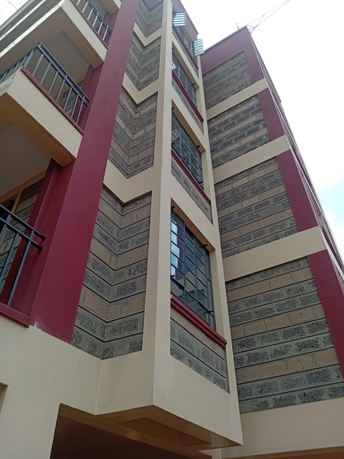 Modern multi-story residential building with burgundy and cream facade