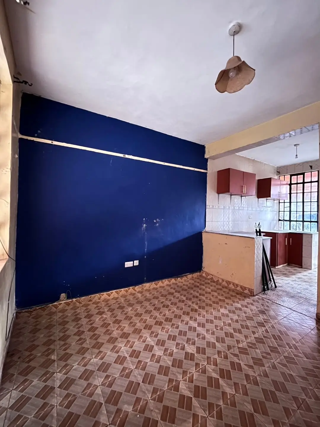 Open-plan living room with blue feature wall, adjacent kitchen visible