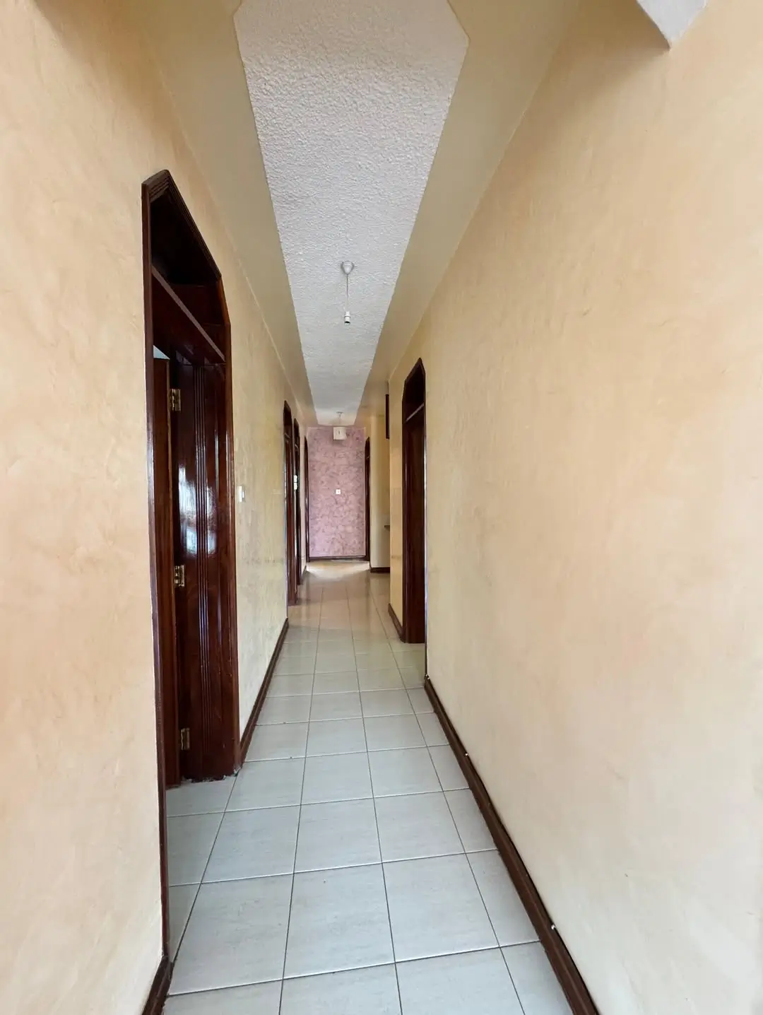 Long corridor with tiled floor and wooden doors