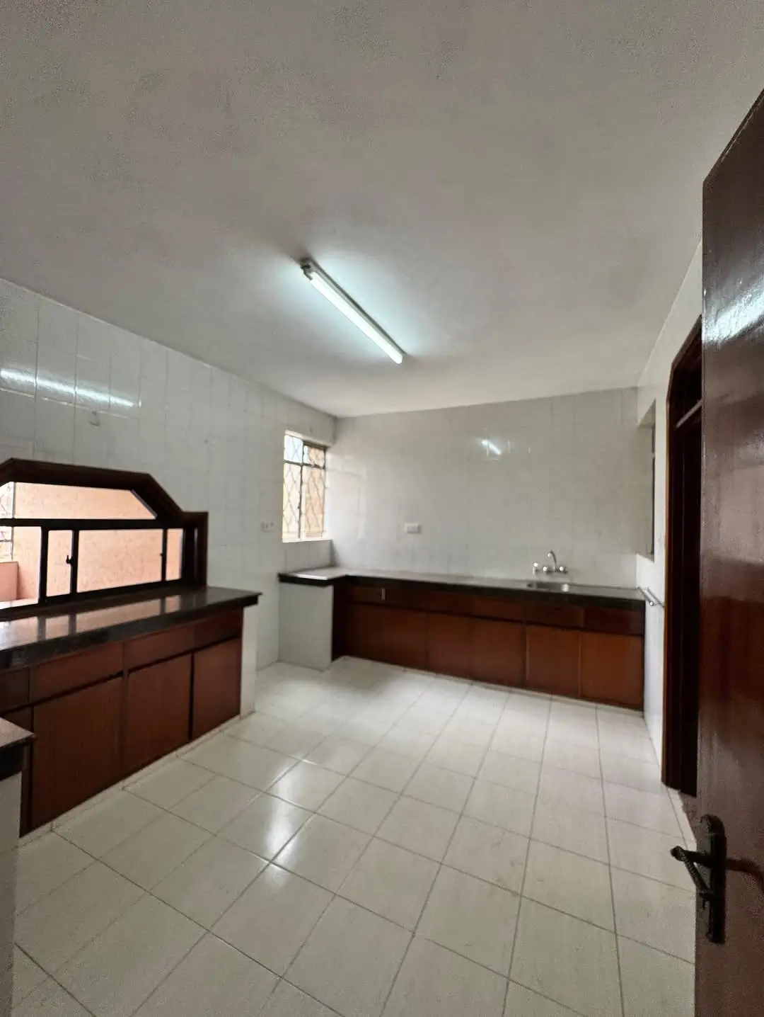 Spacious bedroom with wooden bed frame and tiled flooring