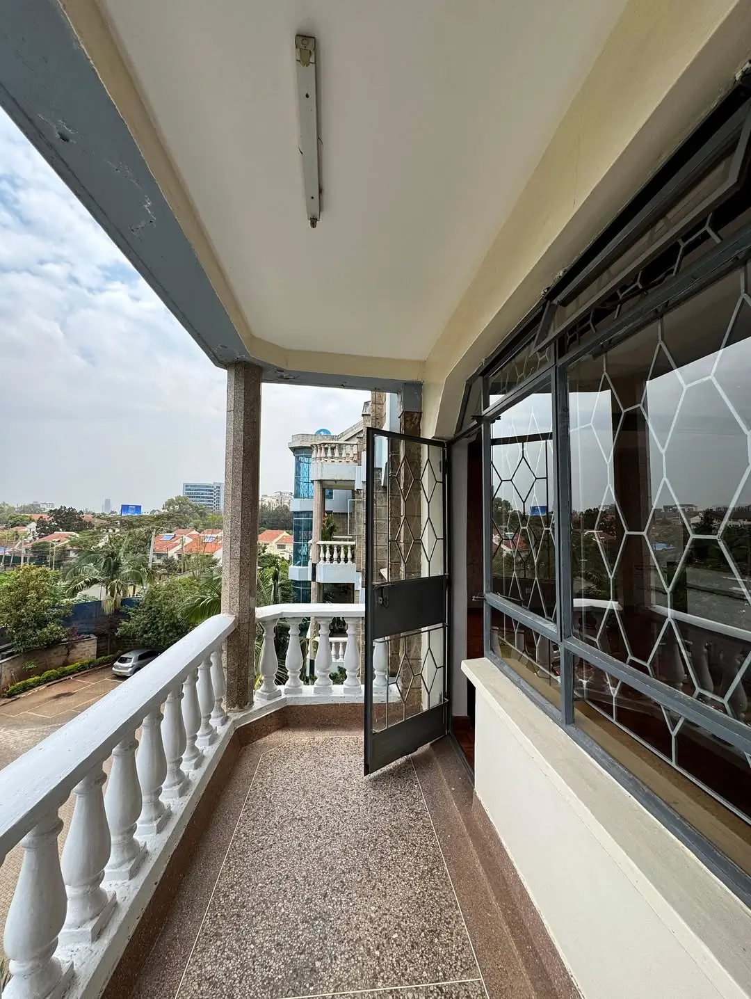 Covered balcony with city views and white railings
