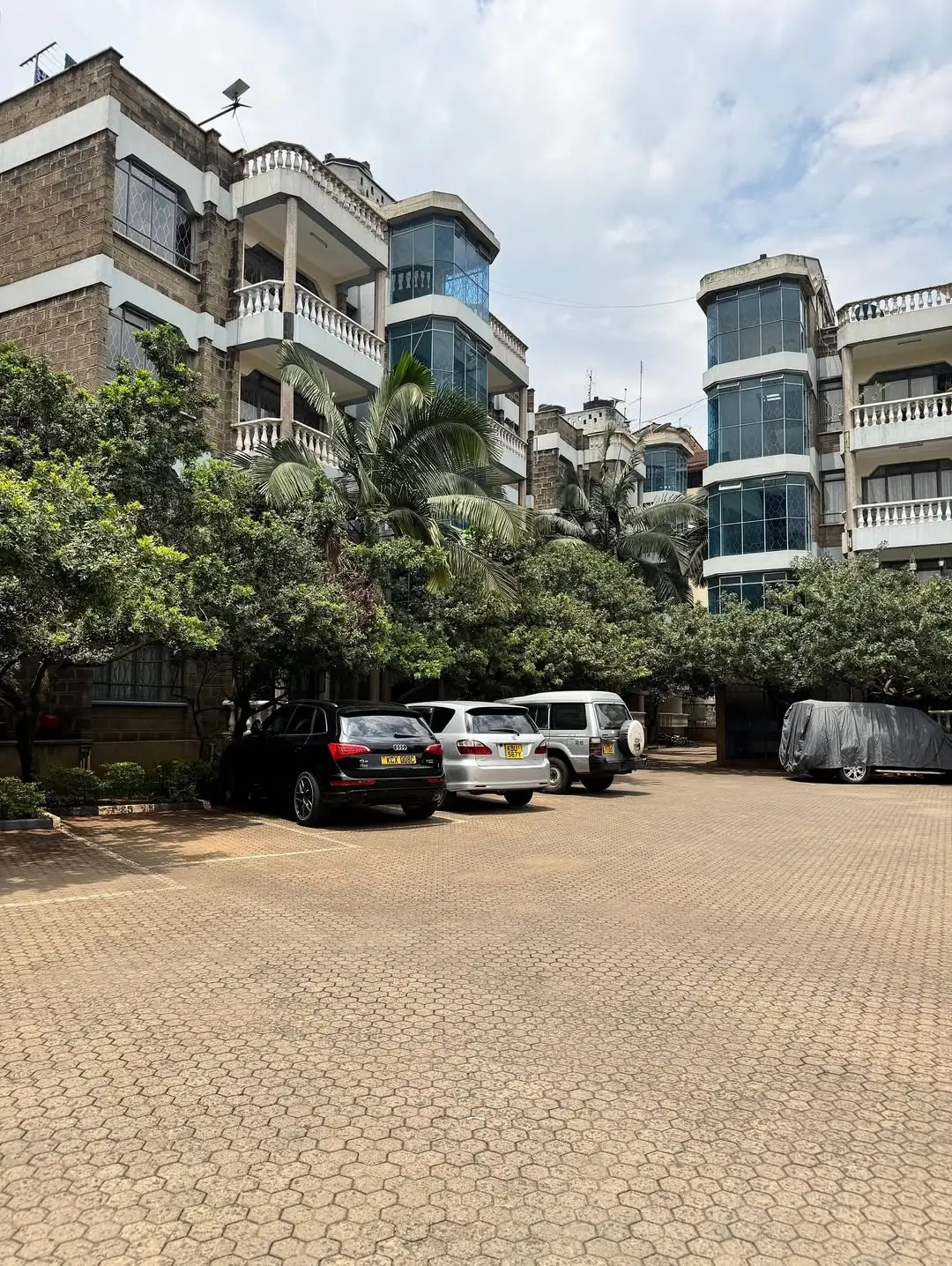 Secure compound parking area with multiple vehicles and residential buildings