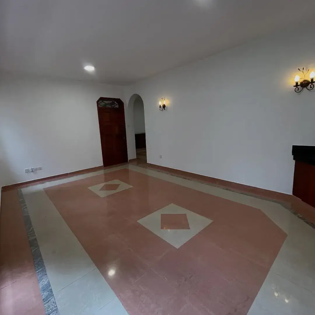 Spacious living room with decorative floor pattern and wall sconces