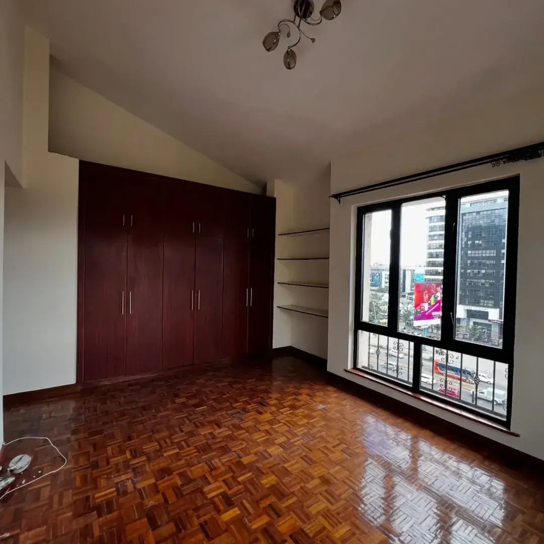 Spacious bedroom with built-in dark wood wardrobe and city views