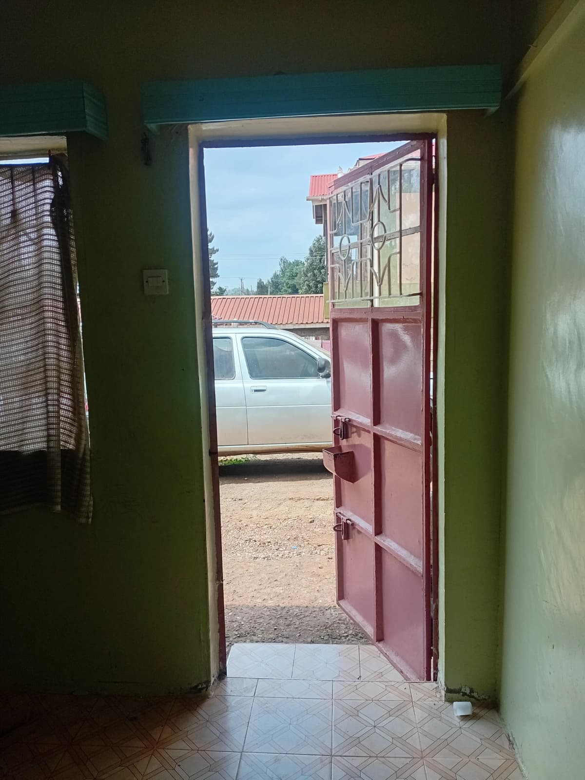 Interior hallway with red entrance door opening to compound